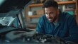 © kineter_ai - Confident 30-year-old White male mechanic in work uniform, smiling while tightening engine bolts under car hood in an organized garage with automotive parts displayed.