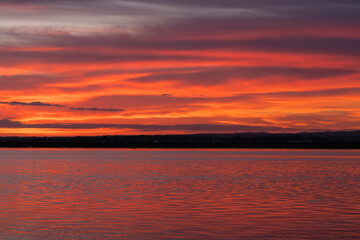 Fototapete - Atardecer de colores vibrantes cerca del Río