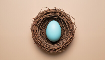 Minimalist flat lay of a pastel blue Easter egg in a natural nest on a beige background