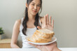© KMPZZZ - Gluten allergy, asian young woman hand push out, refusing to eat white bread slice on plate in breakfast food meal at home, girl having a stomach ache. Gluten intolerant and Gluten free diet concept.