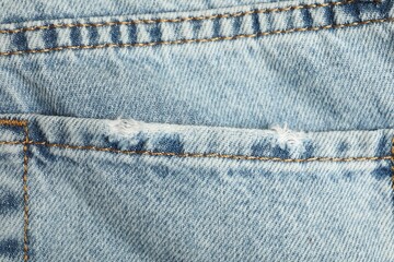 Wall Mural - Ripped light blue jeans with pocket as background, top view