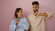 © Krakenimages.com - Woman looking shocked while man gives thumbs down gesture against pink background