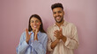 © Krakenimages.com - Man and woman clapping together, smiling and standing against an isolated pink background, showcasing joy and positive vibes in a candid relationship moment