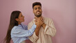 © Krakenimages.com - Woman choking man against pink background, displaying aggressive relationship dynamics in an isolated setting.