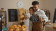 © Krakenimages.com - Happy bakers holding open sign in cozy bakery together