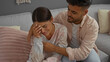 © Krakenimages.com - Woman crying while the man comforts her on a couch showing their relationship and love in a cozy indoor living room