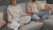 © Krakenimages.com - Man and woman meditating together in living room, sitting on couch with legs crossed, serene and focused in indoor setting, demonstrating relaxation, peace, and mindfulness