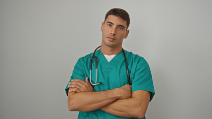 Young man wearing green scrubs with a stethoscope around his neck standing confidently against an isolated white background healthcare and professional setting implied