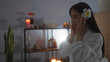 © Krakenimages.com - Woman enjoying spa experience, dressed in a white robe, surrounded by candles and wellness decor, in a serene indoor salon setting.