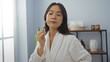 © Krakenimages.com - Woman enjoying a facial massage with a jade roller in a serene spa room, wearing a white bathrobe inside a wellness center