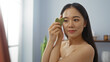 © Krakenimages.com - Young chinese woman using jade roller in spa wellness center room, displaying beauty and relaxation