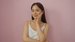 © Krakenimages.com - Beautiful young chinese woman smiling confidently with her hand on her face, isolated against a pink background wall.