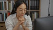 © Krakenimages.com - Woman working in office, wearing glasses and headset, engaged in an online meeting in an indoor workplace environment, surrounded by bookshelves and files