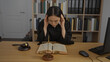 © Krakenimages.com - Chinese female judge in office reading law book with scales and gavel on desk