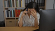 © Krakenimages.com - Woman in office stressed on the phone with hand on head in indoor workplace surrounded by books and folders