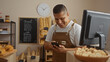 © Krakenimages.com - Handsome young hispanic man smiling in a bakery shop interior wearing an apron while using his phone for business purposes