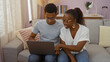 © Krakenimages.com - Mother and son sitting together in the living room of an apartment using a laptop, demonstrating love and family connection in an indoor setting