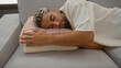 © Krakenimages.com - Young man sleeping peacefully on a couch in a cozy living room with a soft pillow beneath his head.