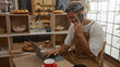 © Krakenimages.com - Handome man in bakery working on a laptop while talking on phone with coffee in the background