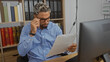 © Krakenimages.com - Young, arab, bearded, handsome man in glasses looking surprised while reading a document in an office setting with bookshelves in the background