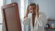 © Krakenimages.com - Handsome young arab man in a spa salon wearing a white robe adjusting his hair while looking in the mirror and smiling indoors