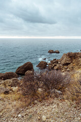 Wall Mural - coastal view with rocky shoreline and cloudy sky at sunset