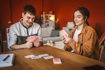 Wall Mural - young couple boyfriend and girlfriend play cards at home