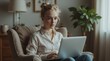 © елена калиничева - Young woman in casual attire sits in a cozy armchair using a laptop, with soft natural light from a window creating a warm atmosphere