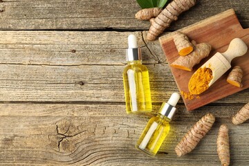 Canvas Print - Tumeric oil, powder and roots on wooden table, flat lay. Space for text