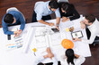 © InfiniteFlow - Top view banner of diverse group of civil engineer and client working together on architectural project, reviewing construction plan and building blueprint at meeting table. Prudent