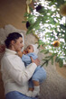 © saulich84 - A mother in a white sweater lying with her daughter for 1 year on the floor by the Christmas tree in an apartment on New Year's Eve