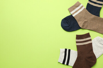 Wall Mural - Different comfortable socks on light green background, flat lay. Space for text