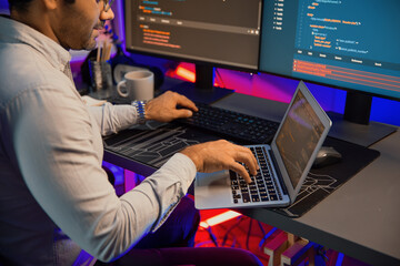 Wall Mural - smart it developer working on laptop to type searching in software coding system at neon light offic