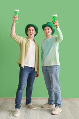 Wall Mural - Young men with beer near green wall. St. Patrick's Day celebration