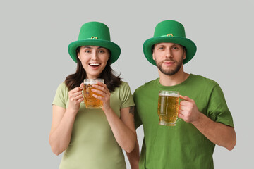 Wall Mural - Beautiful young couple in leprechaun hats with glasses of beer on grey background. St. Patrick's Day celebration