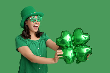 Canvas Print - Beautiful young woman in leprechaun hat and decorative glasses with air balloon in shape of clover on green background. St. Patrick's Day celebration