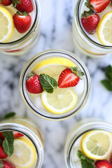 Wall Mural - Jars of refreshing lemonade, filled with ice, lemon slices, strawberries, and mint leaves, viewed from overhead.