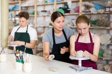 Potter teaches teenagers how to make pottery out of clay in a workshop