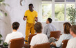 © JackF - African american man leads a lecture in the audience during a group meeting of men gays