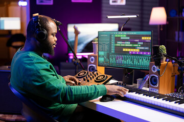 Leinwandbilder - Sound producer operating on mixing console and piano keys in home studio, editing his audio recorded files on DAW software. Recording expert enhancing quality on old recordings.