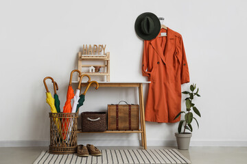 Wall Mural - Coffee table, basket with umbrellas and hanging coat in interior of hallway