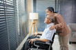 © offsuperphoto - senior woman standing beside senior man sitting on wheelchair and looking outside at home