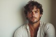 © kura - A young man with wavy brown hair poses against a wall