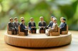 © Maki_Japan - スーツ姿の木製のミニチュアビジネスマンたちが重要な会議を行っている（チームワーク・話し合い・説明・意思決定）