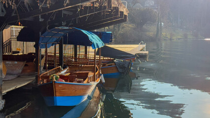rustic wooden boats under a bridge on a misty lake, tranquil travel, wanderlust escape