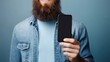© felix_brönnimann - Man holding smartphone with blank screen in casual attire, showcasing modern technology and lifestyle against a blue background