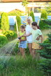© Nadya Kolobova - Mother and Children Using Drip Irrigation to Water Flowers. a mother and her two children watering flowers in their garden using a drip irrigation hose. they enjoy the process of nurturing