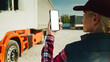 © VAKSMANV - Truck driver holding smartphone mockup of blank screen.