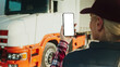 © VAKSMANV - Truck driver holding smartphone mockup of blank screen.