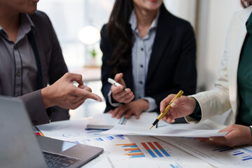 Group of business professionals collaborating on financial reports, discussing data and making strategic decisions. Charts and graphs on the table highlight teamwork and analysis